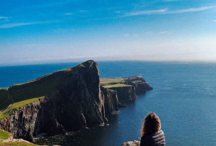 ragazza seduta di spalle che guarda Neist Point in Scozia